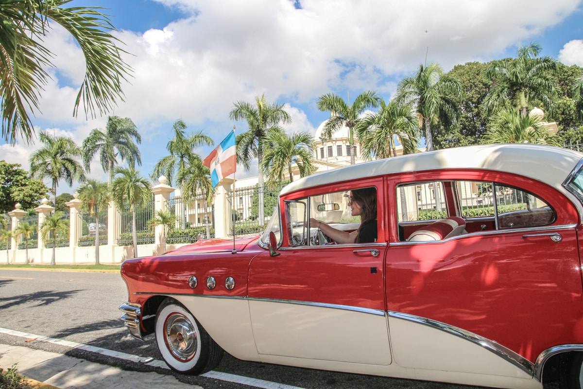 Une voiture ancienne des années 50 garée devant un bâtiment colonial coloré à Saint-Domingue