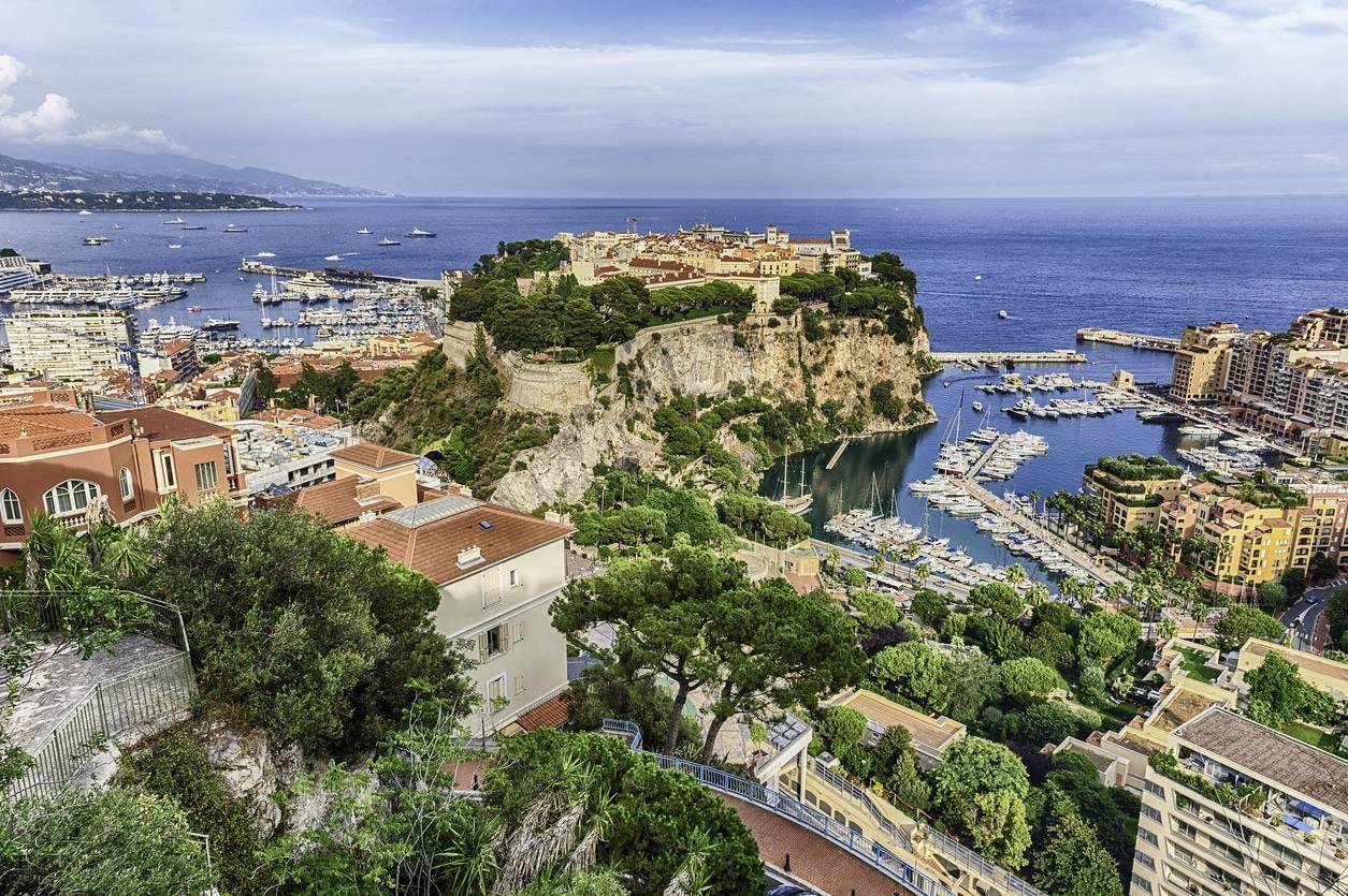 Un monospace privé longeant le port d'Antibes et les yachts de luxe sous un ciel ensoleillé.