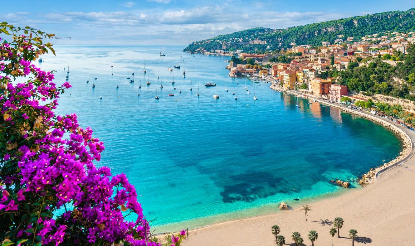 Un minibus à impériale à toit ouvert circulant près du port de la Principauté de Monaco sous un ciel ensoleillé.