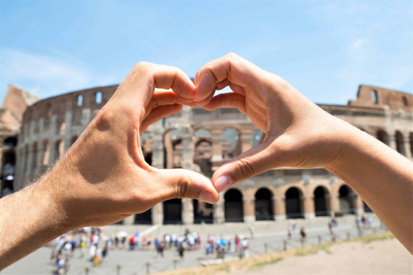Couple formant un coeur avec leurs mains devant le Colisée de Rome