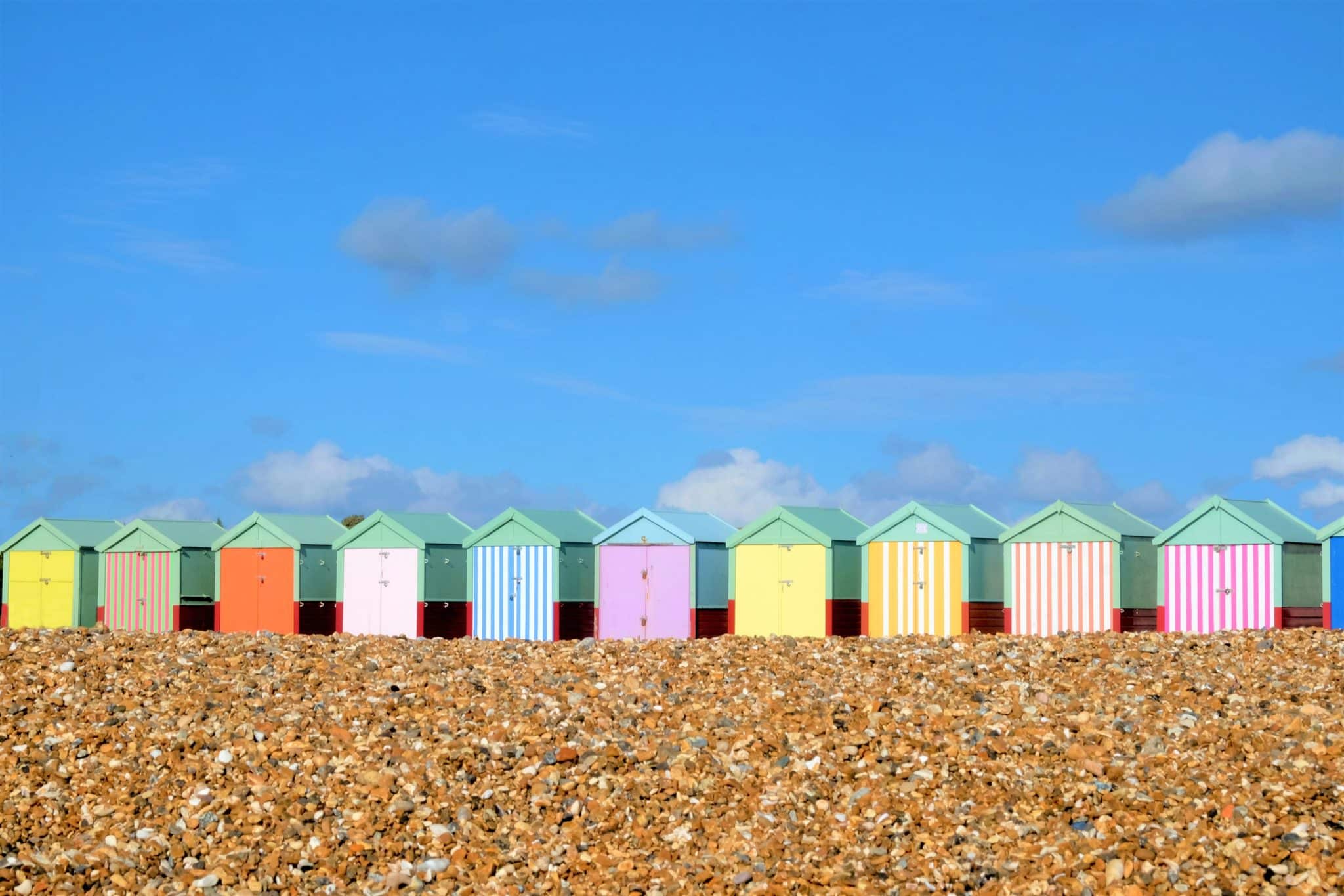 Une gamme de cabines de plage colorées brighton sur une plage de galets avec un ciel bleu
