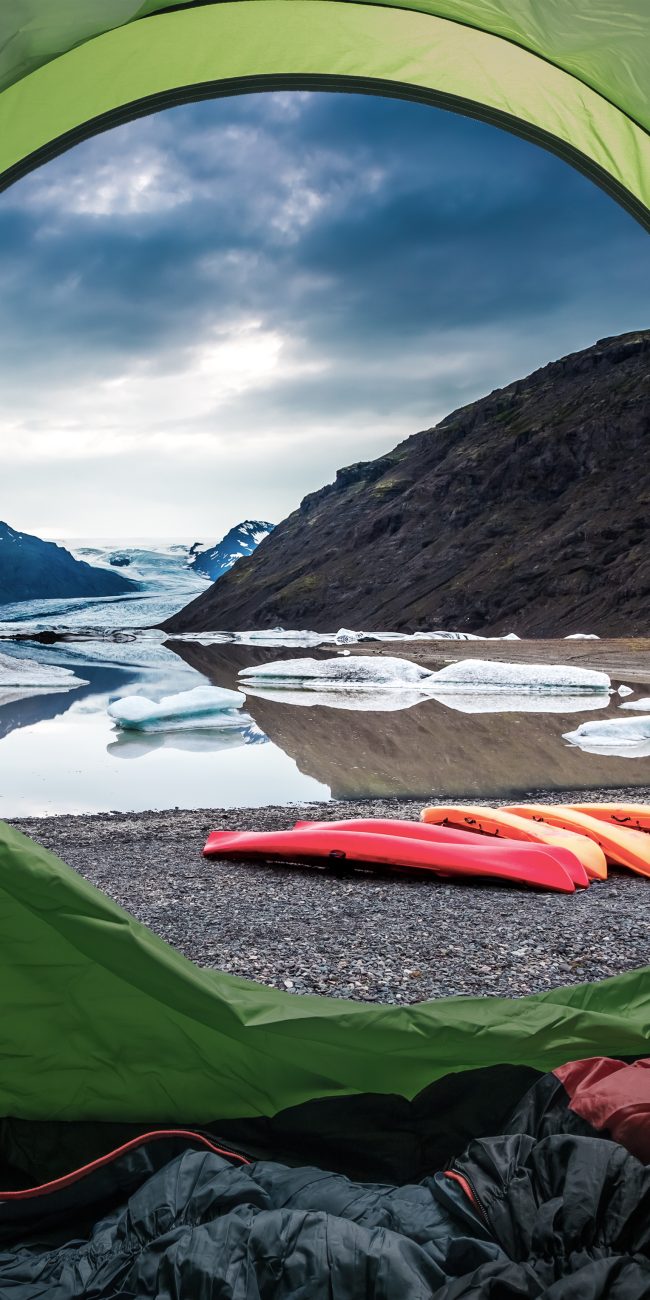 Tente de camping avec vue sur des kayaks et le lagon glaciaire de Jokulsarlon