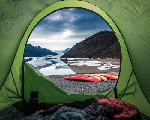 Tente de camping avec vue sur des kayaks et le lagon glaciaire de Jokulsarlon