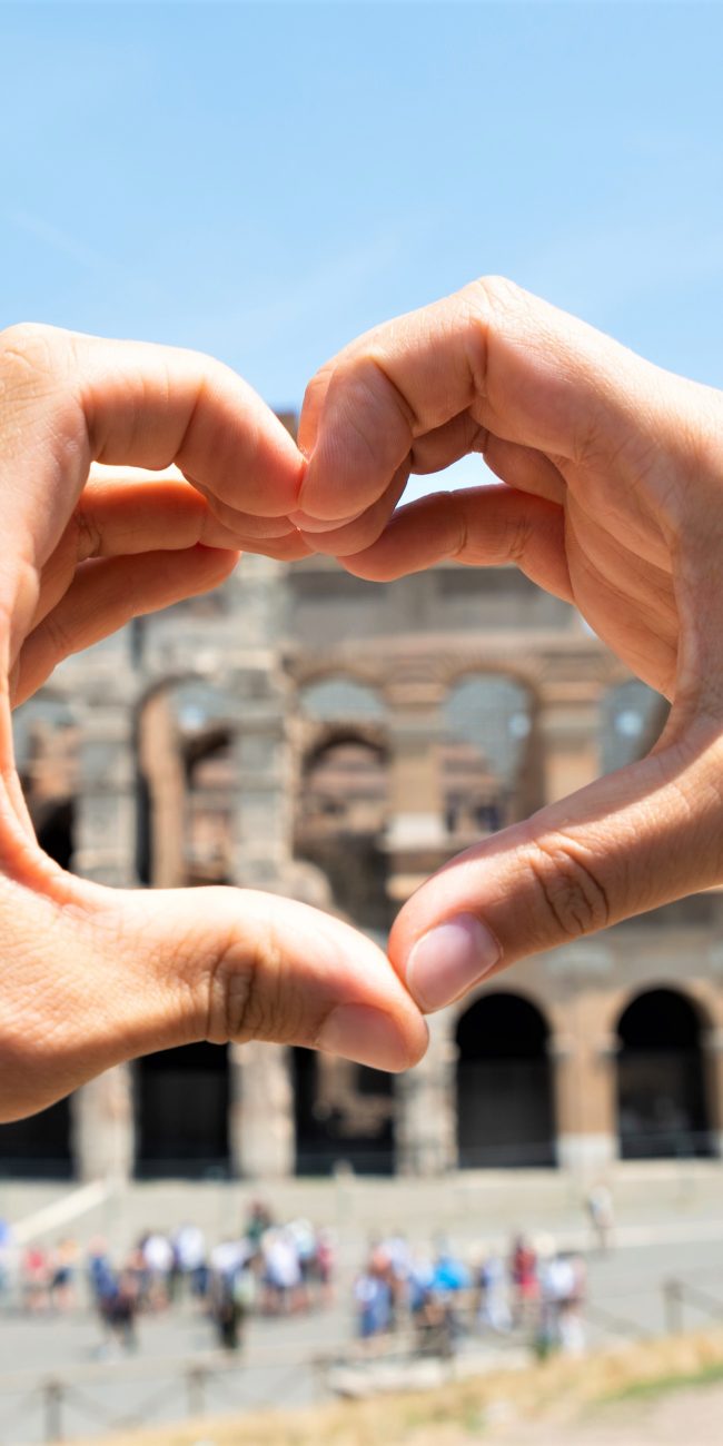 Couple formant un coeur avec leurs mains devant le Colisée de Rome