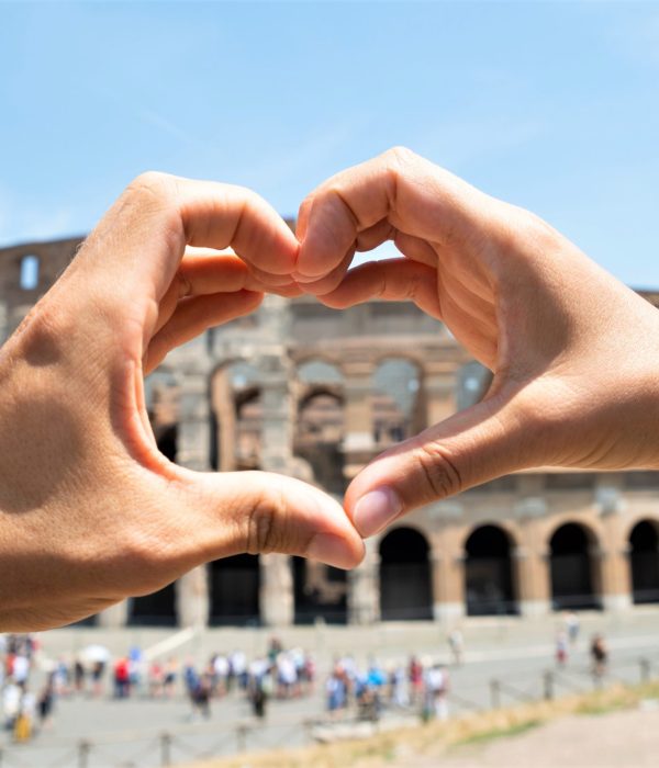 Couple formant un coeur avec leurs mains devant le Colisée de Rome