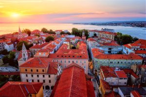 Vue du haut de la vieille ville de Zadar au coucher du soleil depuis la tour de la cathédrale de Zadar, Dalmatie, Croatie. Paysage urbain pittoresque avec architecture historique, toits de tuiles rouges, mer, ciel et soleil, arrière-plan de voyage en plein air, road trip en croatie