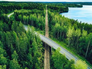 Vue aérienne d'une route de campagne au-dessus de la voie ferrée dans une forêt verte d'été en Finlande.