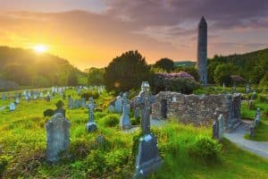Road trip en Irlande : la tour ronde et le cimetière du site monastique de Glendalough, dans le pays de Wicklow, en Irlande.